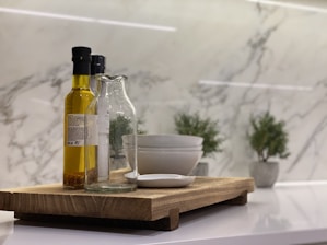 A collection of various cooking oils in clear bottles on a wooden table.