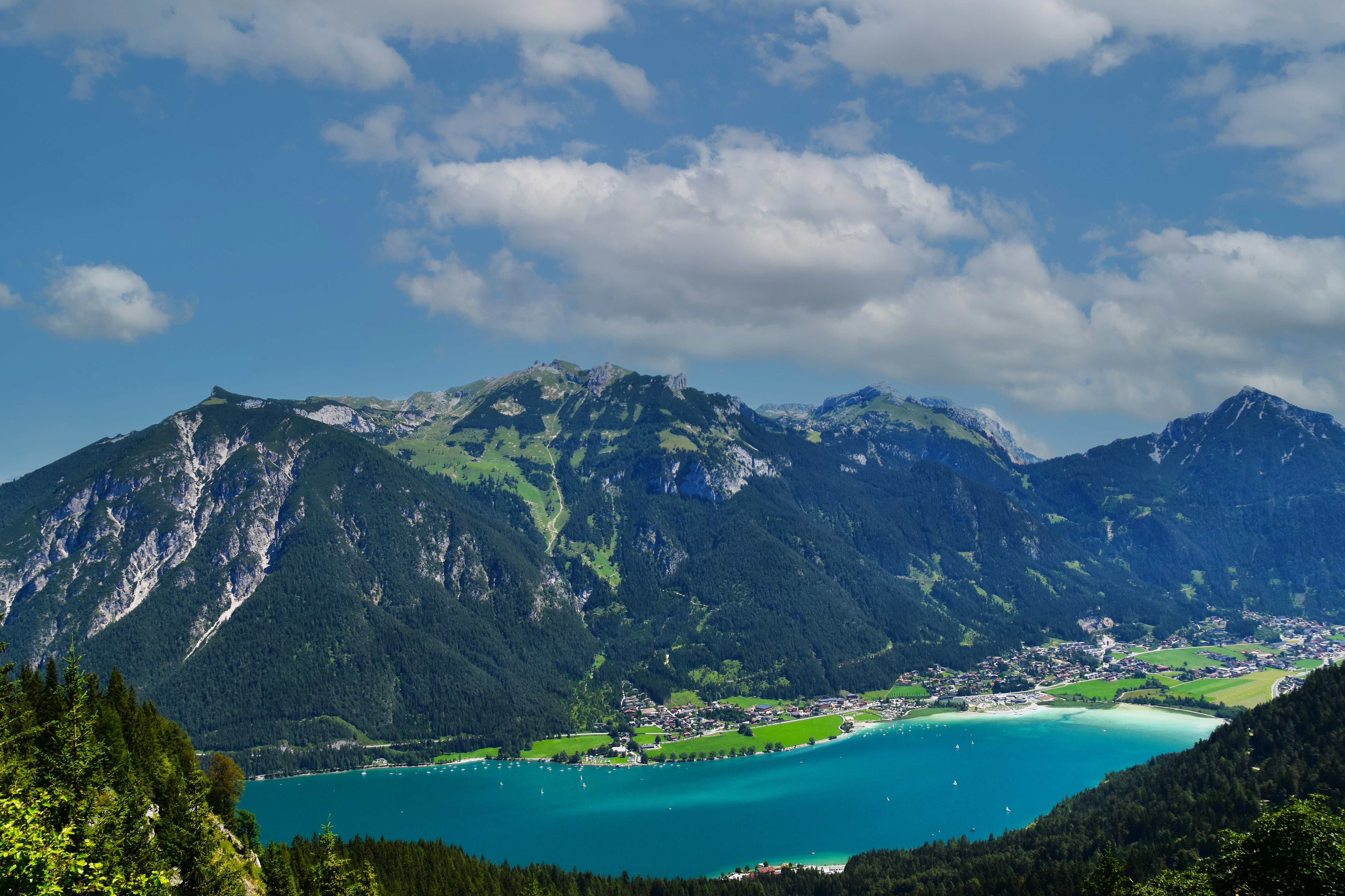 green and gray mountains beside body of water under blue and white cloudy sky during daytime