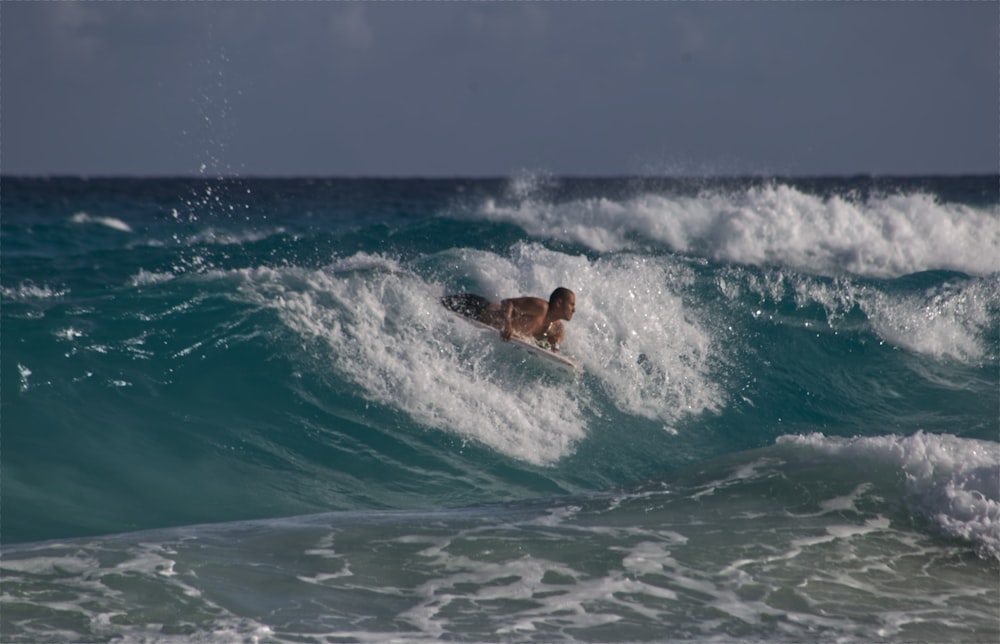 man surfing on sea waves during daytime