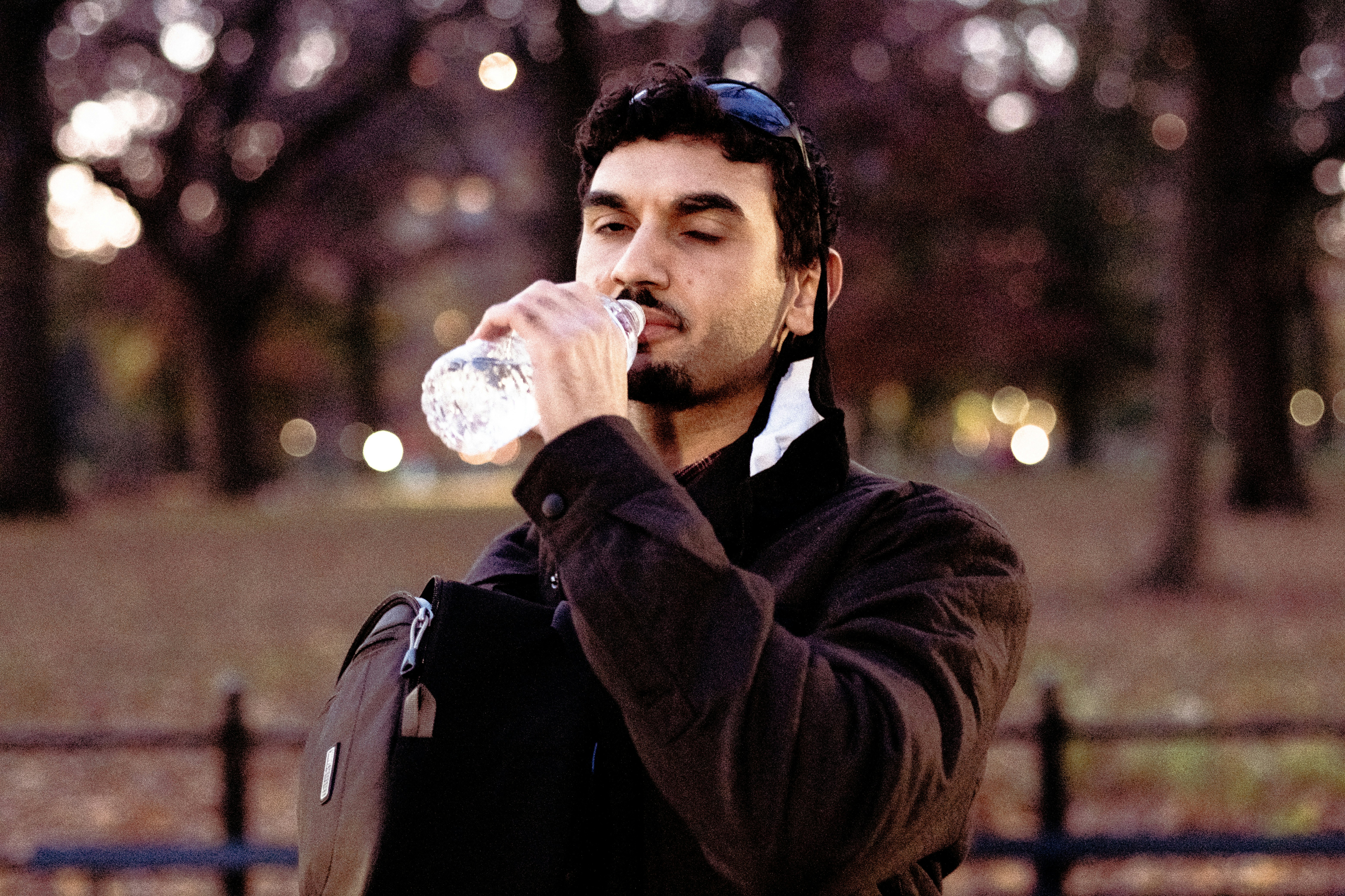man in black jacket drinking water