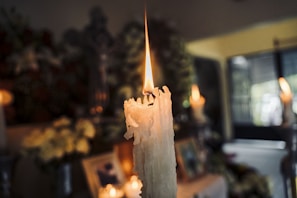 A close-up of a yellow candle with a Saint Michael image, flame burning steadily.