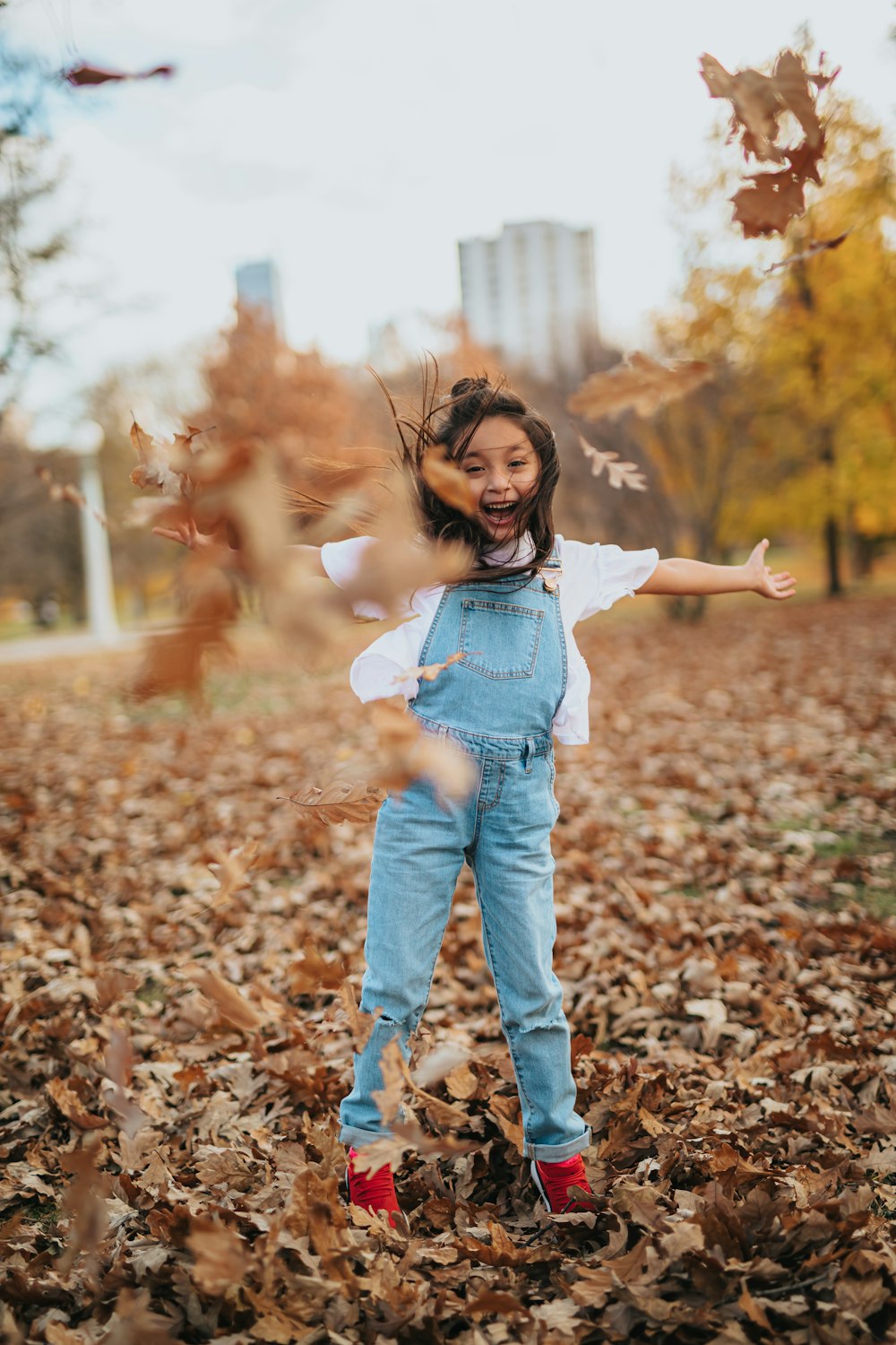 girl in blue denim jacket and blue denim jeans standing on dried leaves during daytime