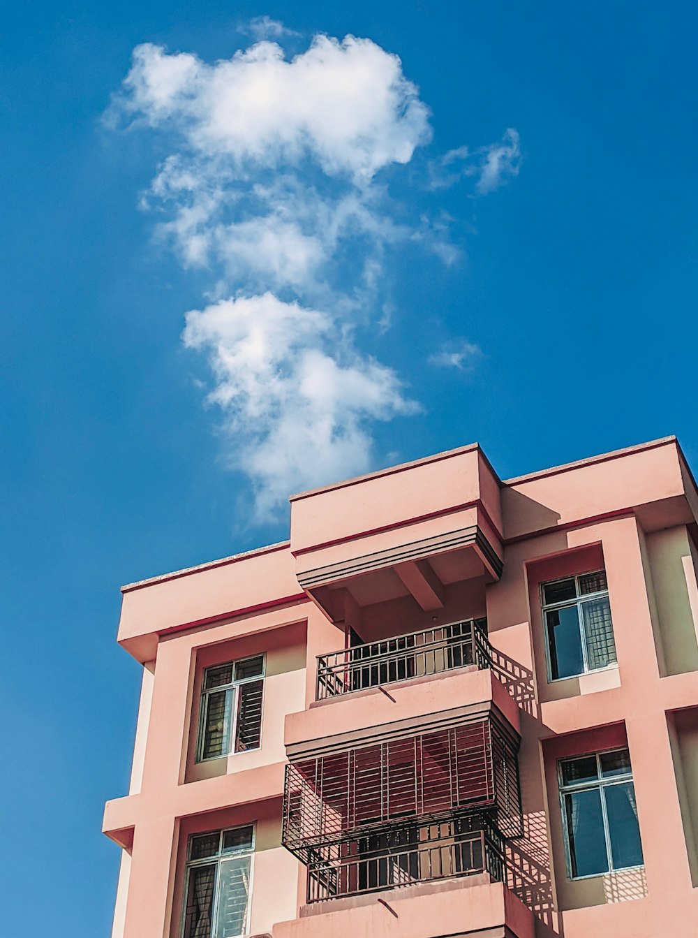 Rosa und weißes Betongebäude unter blauem Himmel tagsüber