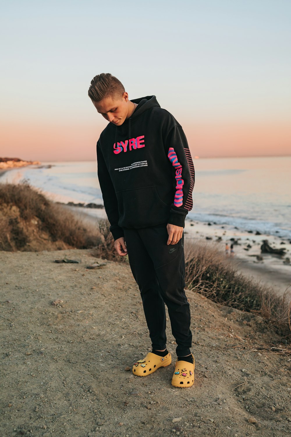 man in black hoodie standing on seashore during daytime