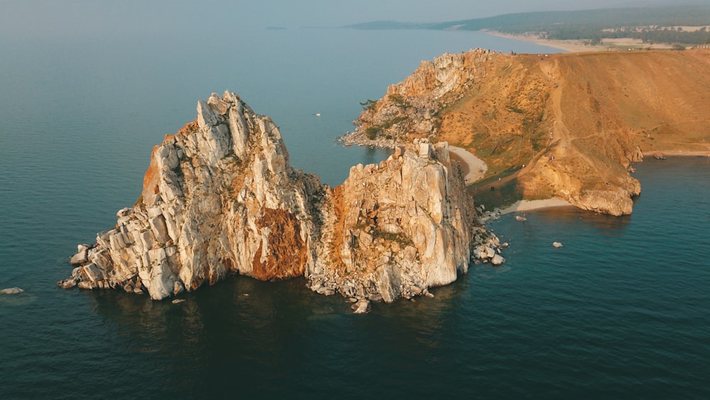 brown rocky mountain beside blue sea during daytime