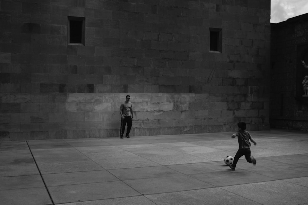 grayscale photo of man and woman walking on sidewalk