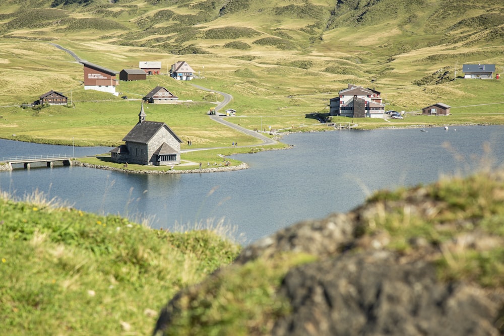 brown wooden house on green grass field near lake during daytime