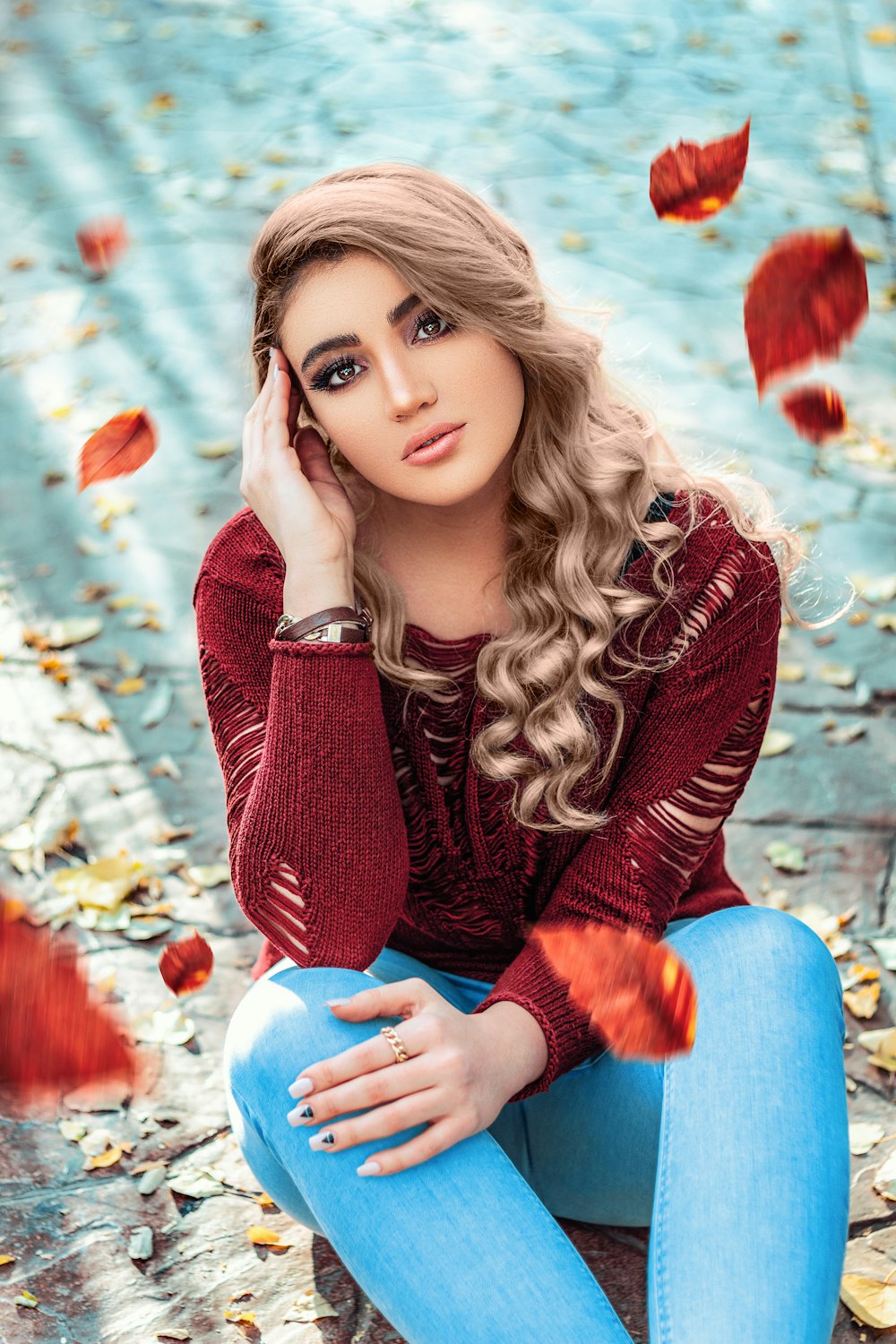 woman in red sweater and blue denim jeans sitting on white and blue ball