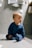 baby in blue long sleeve shirt and blue denim jeans sitting on floor