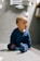 baby in blue long sleeve shirt and blue denim jeans sitting on floor