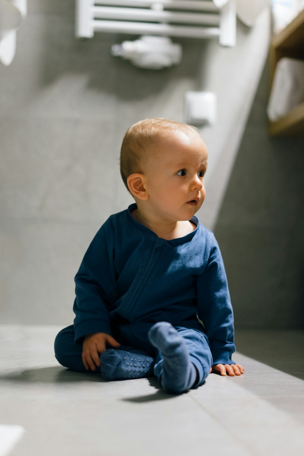 baby in blue long sleeve shirt and blue denim jeans sitting on floor