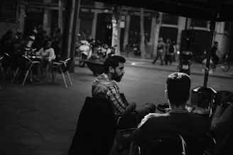 grayscale photo of people sitting on chair