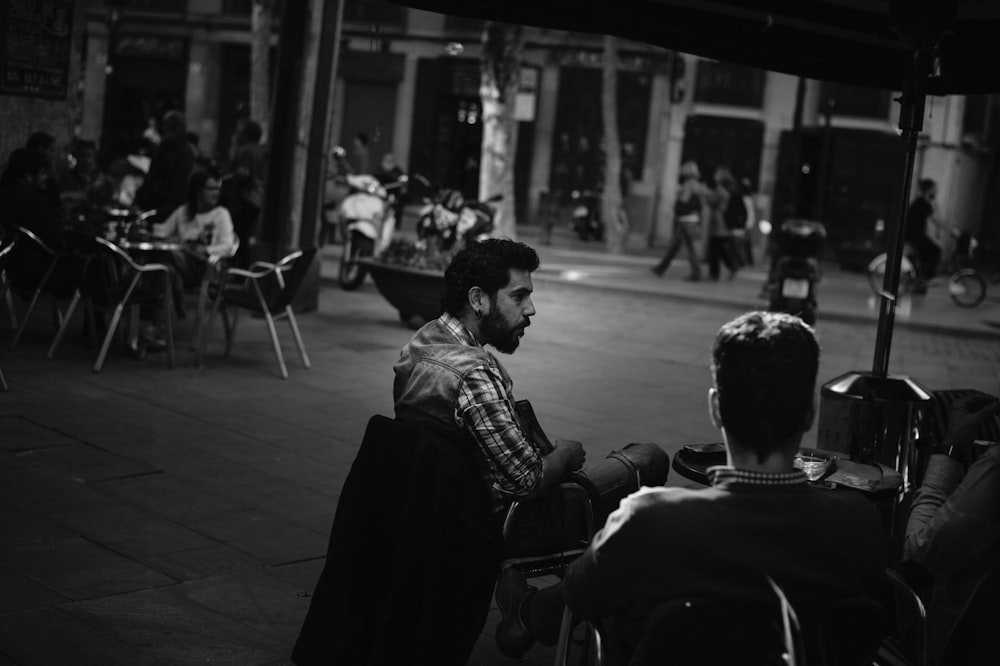 grayscale photo of people sitting on chair