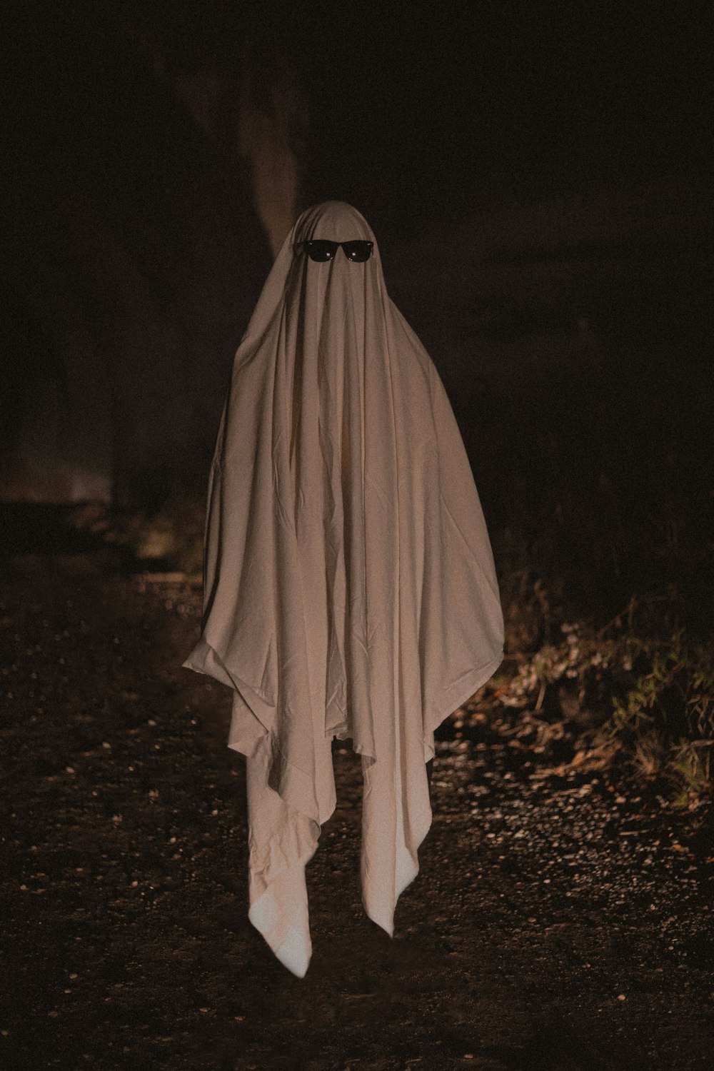 Persona con túnica blanca de pie sobre hojas secas marrones durante la noche