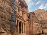 Ancient ruins of Petra carved into rose-red cliffs at sunset.