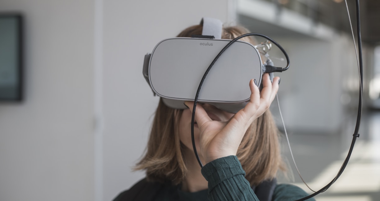 woman in black sweater holding white and black vr goggles