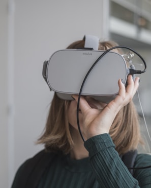 woman in black sweater holding white and black vr goggles