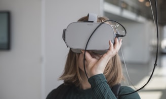 woman in black sweater holding white and black vr goggles