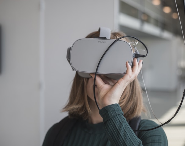 woman in black sweater holding white and black vr goggles