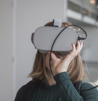 woman in black sweater holding white and black vr goggles