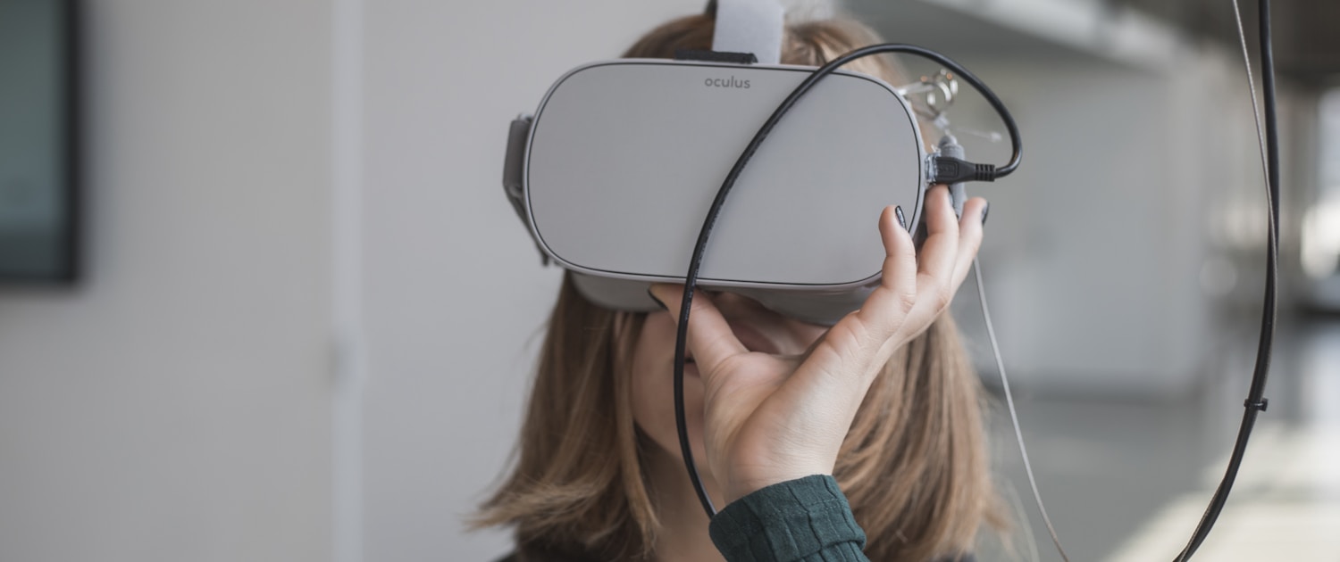 woman in black sweater holding white and black vr goggles