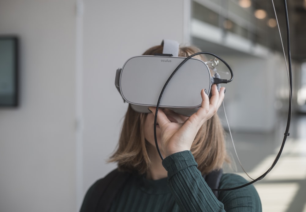 woman in black sweater holding white and black vr goggles