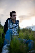 A smiling teen journaling outdoors under a deep charcoal sky at dusk.