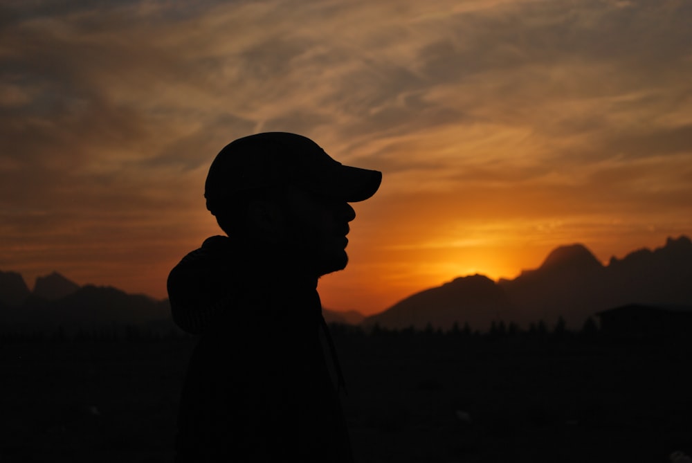 silhouette of man wearing hat during sunset