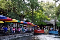 people riding on red boat on river during daytime