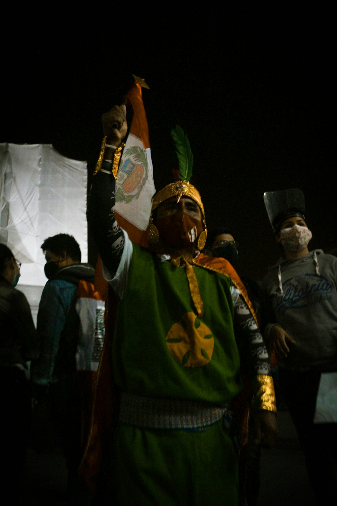 man in green and gold costume standing beside man in black jacket