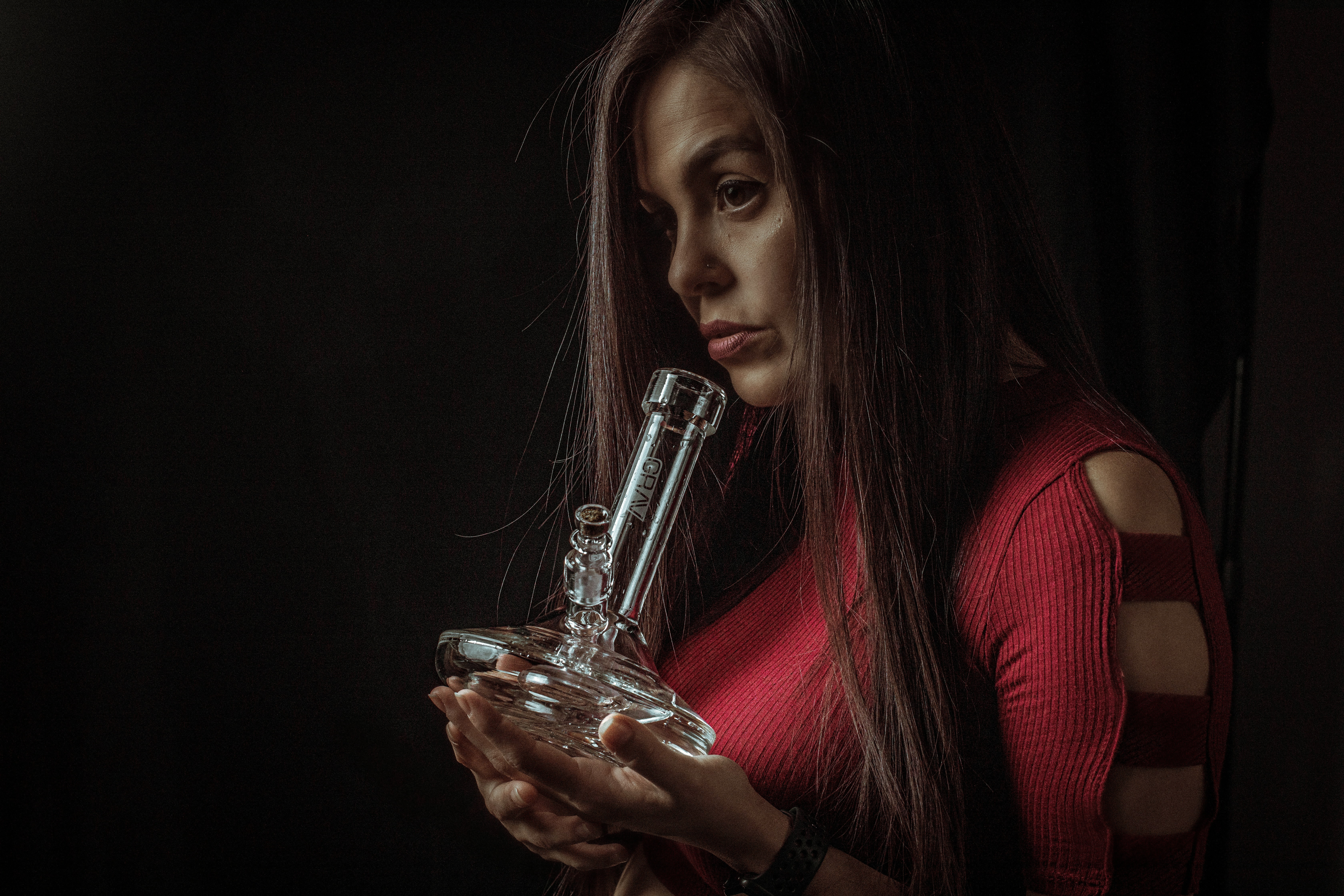 woman in red long sleeve shirt holding clear glass bottle
