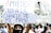 A person holds a sign in Spanish that reads '¿Miedo? Solo a la chancla de mi mamá' during a public protest. The crowd behind appears to be participating in the demonstration, with many people wearing masks and helmets. The background includes a large building with a mural or banner.