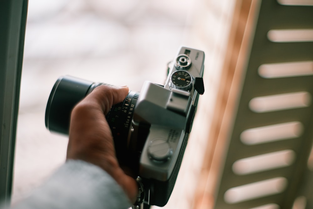 person holding black and silver camera