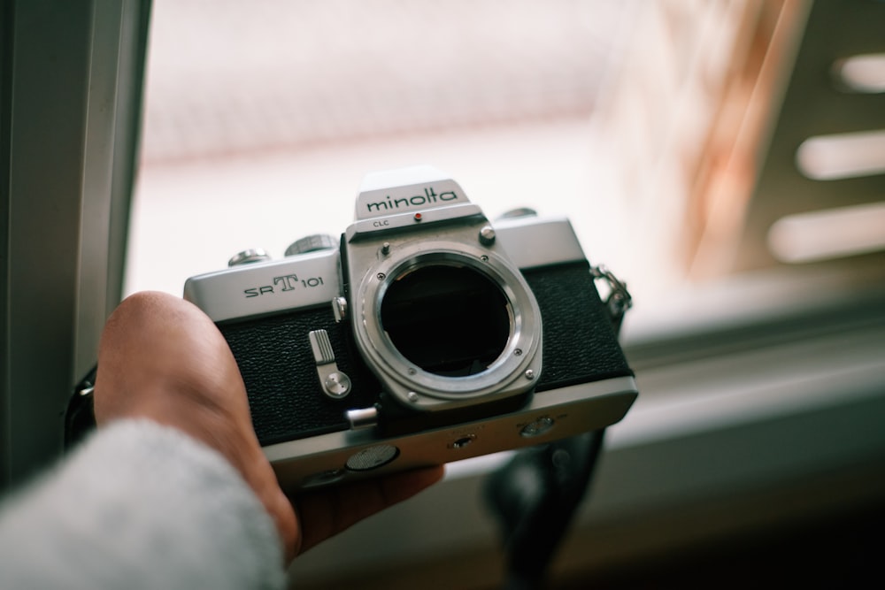 person holding gray and black canon dslr camera