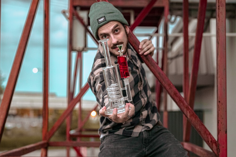 man in black and white checkered long sleeve shirt holding clear glass bottle