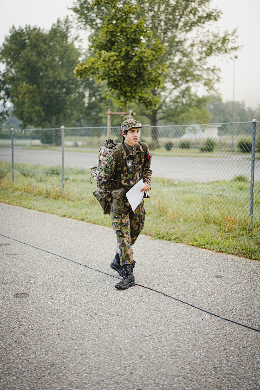 man in black and brown camouflage uniform standing on road during daytime