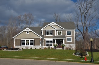 white and brown wooden house near bare trees under blue sky during daytime