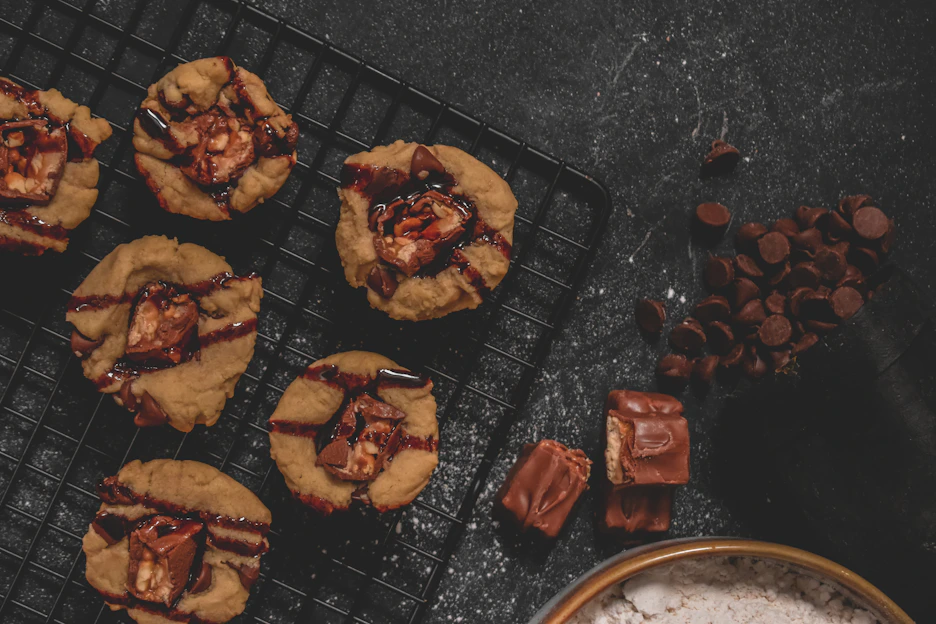 Close-up of a warm chocolate chip cookie with melting chips on a rustic wooden table