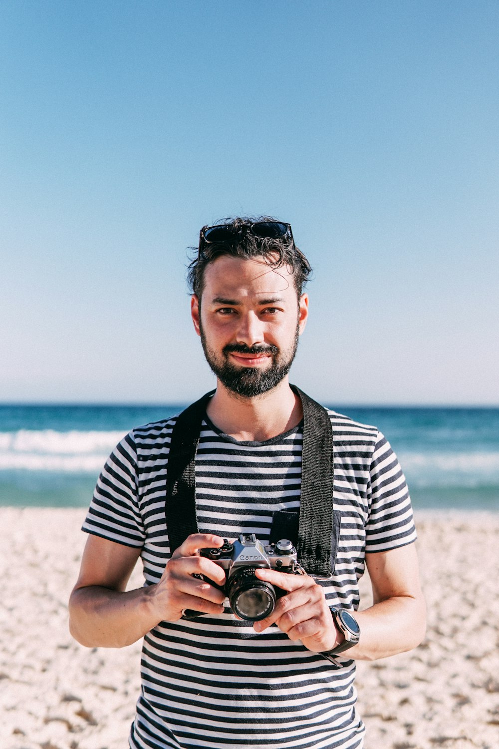 man in black and white striped crew neck t-shirt holding black dslr camera