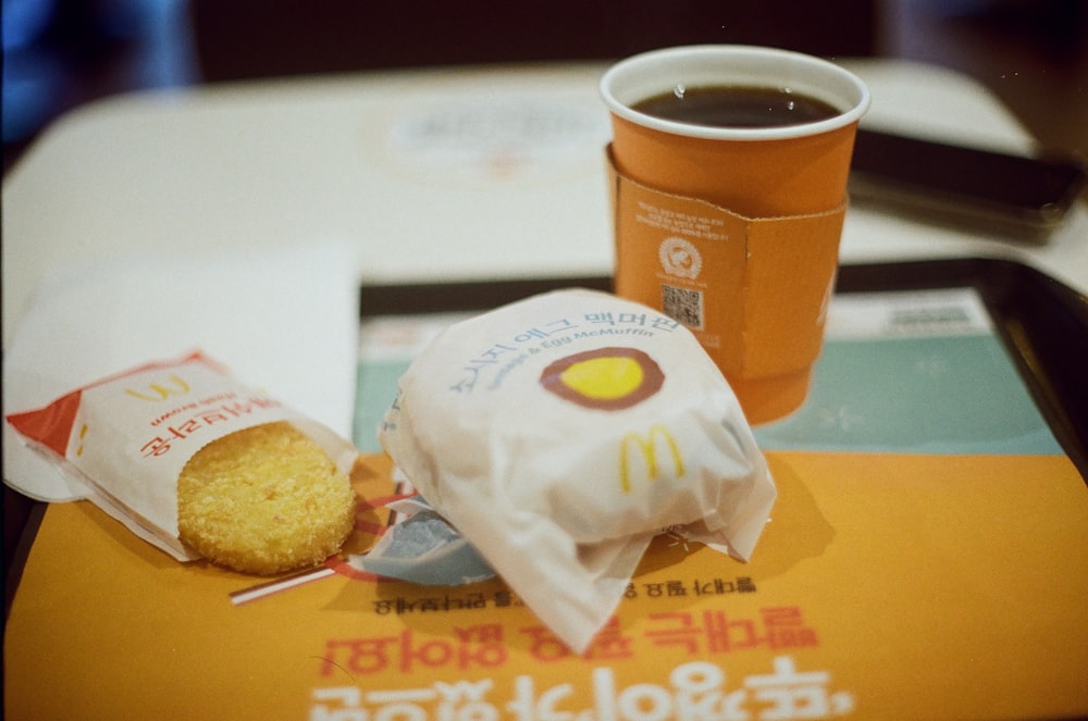 white and orange plastic cup beside brown bread