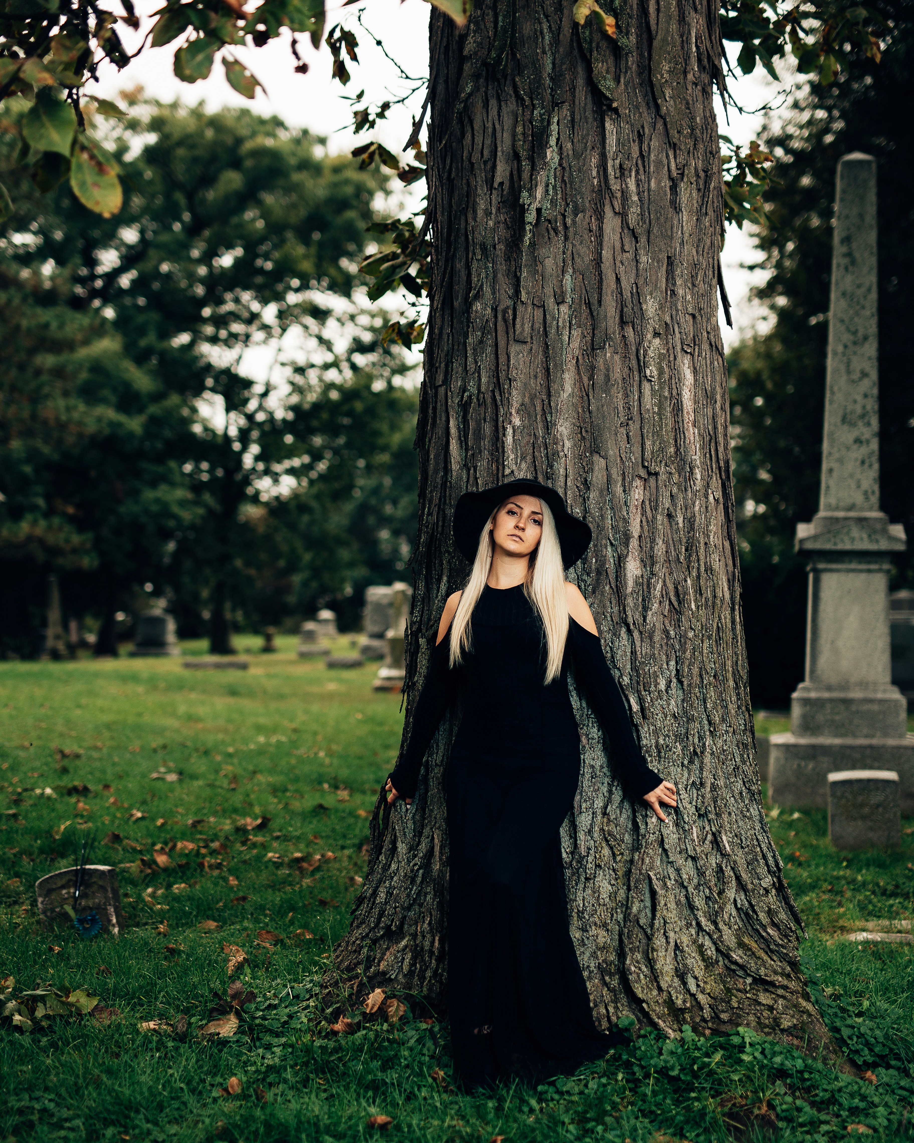 woman in black dress standing beside tree