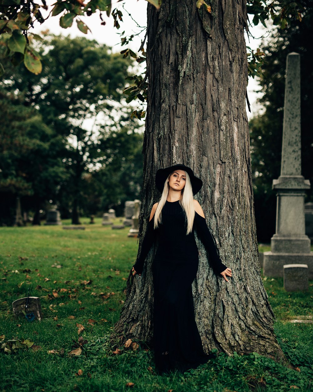 woman in black dress standing beside tree