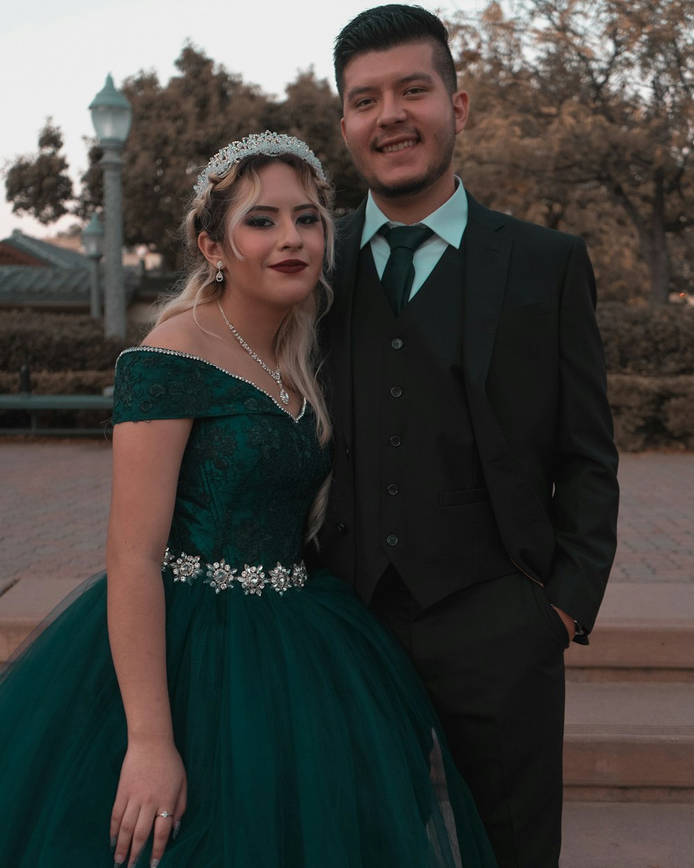 man in black suit jacket beside woman in green dress