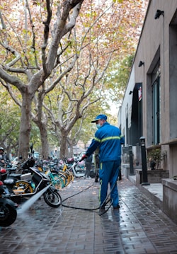 man in blue jacket and blue denim jeans standing beside black motorcycle during daytime