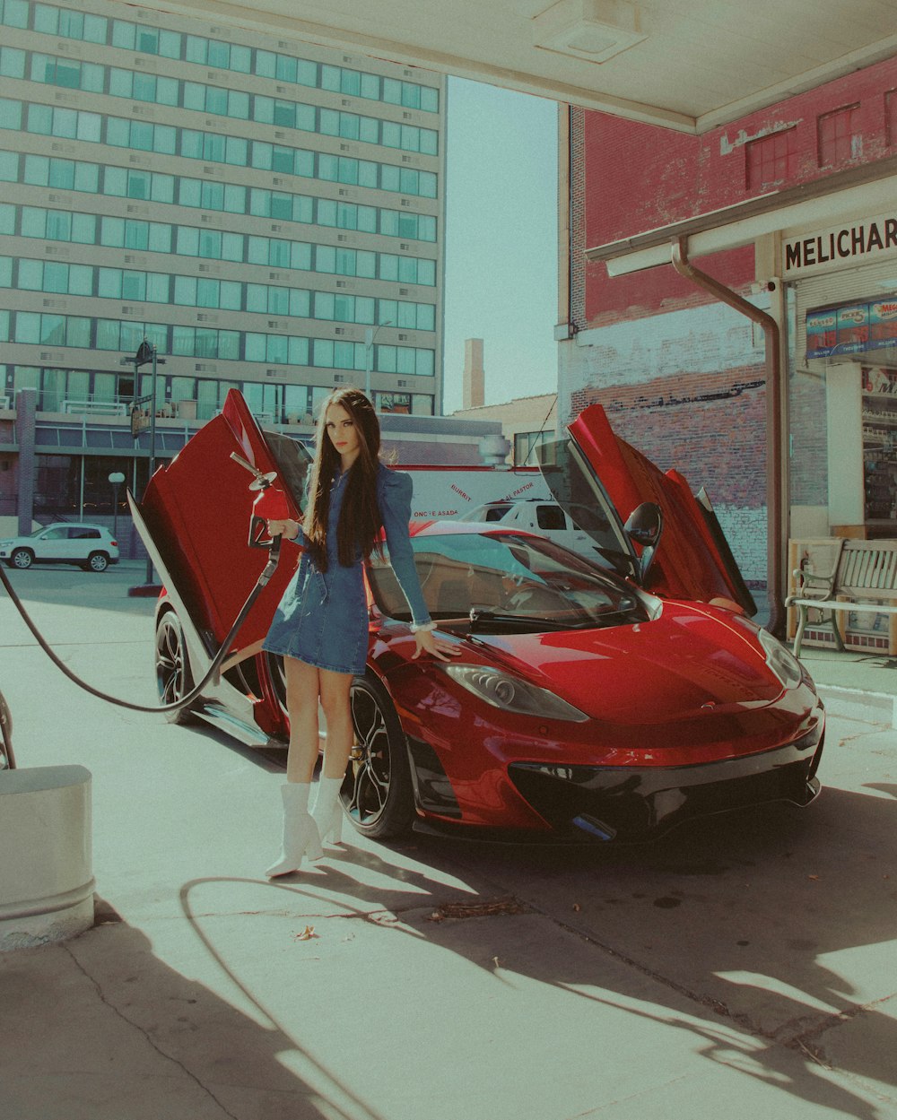 woman in blue dress standing beside red car during daytime