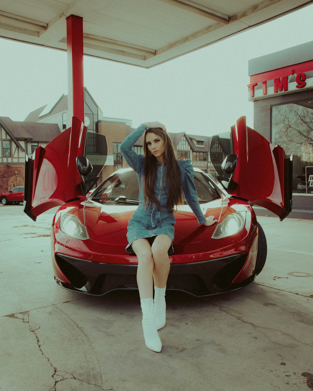 a woman sitting on top of a red sports car