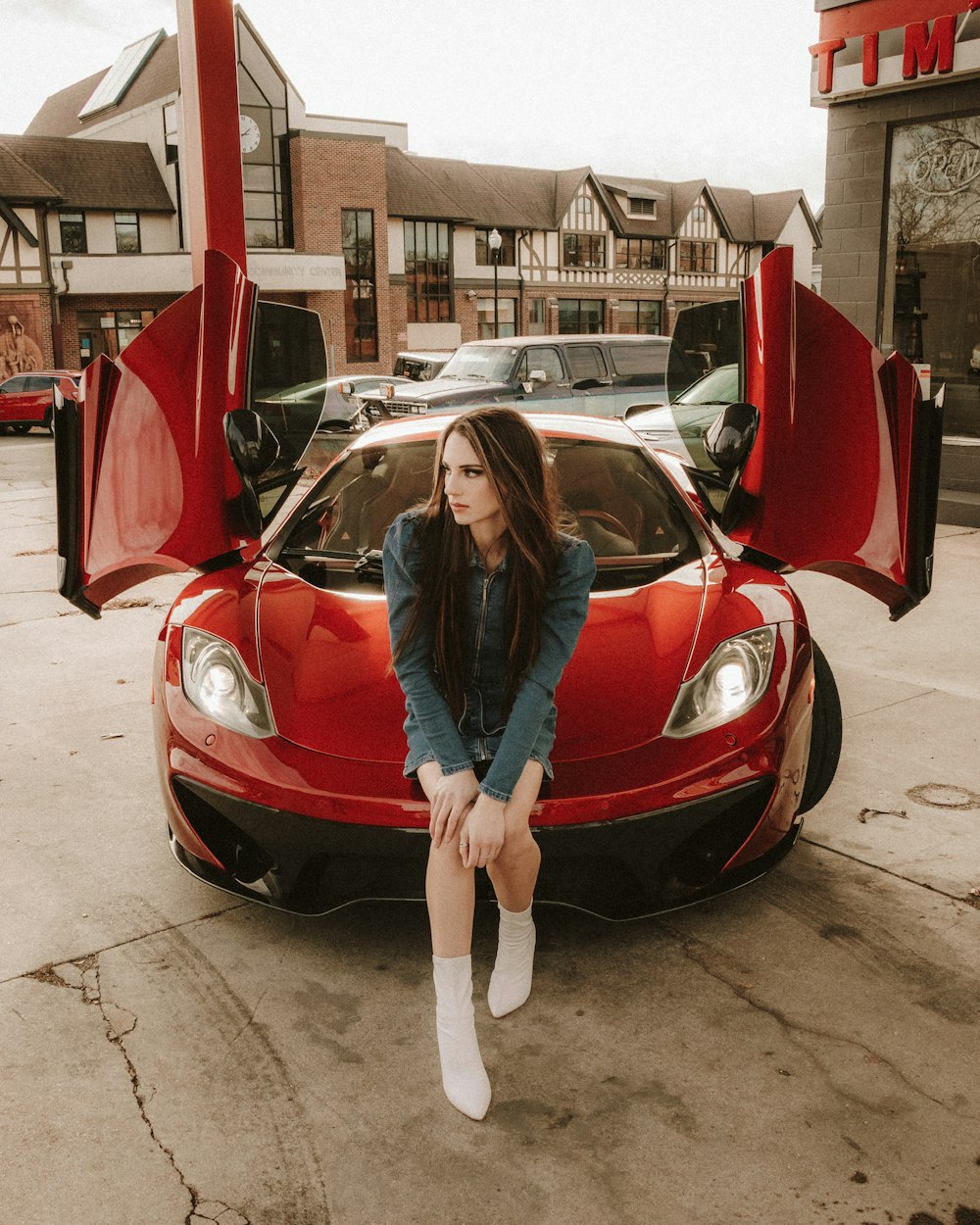 woman in blue jacket standing beside red car during daytime