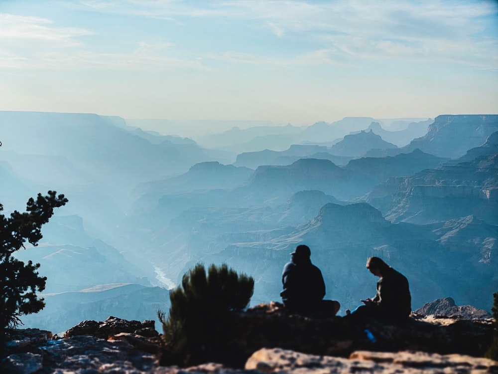 2 person sitting on rock formation during daytime