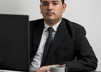 man in black suit jacket holding white ceramic mug