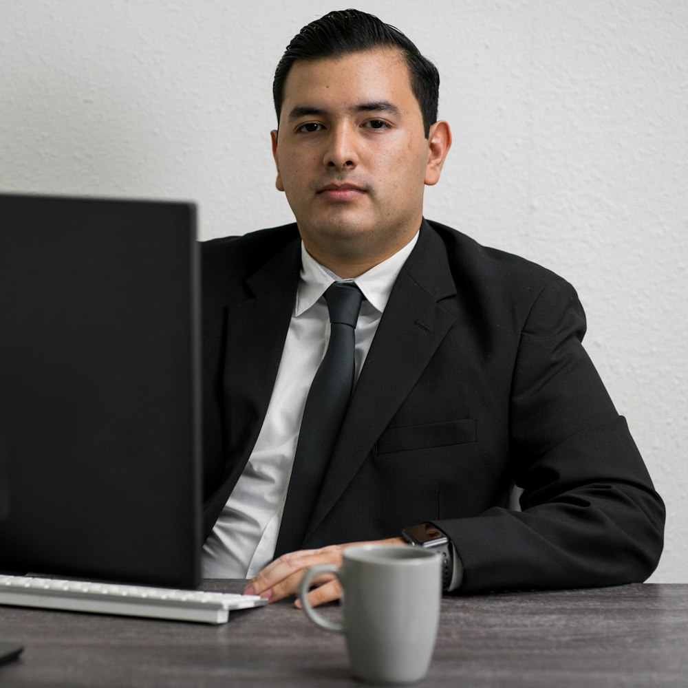 man in black suit jacket holding white ceramic mug